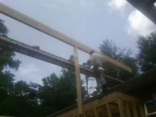 Carpenter setting a ridge beam over a new addition frame — Ice Dam Removal by Roofing Brothers in Moline