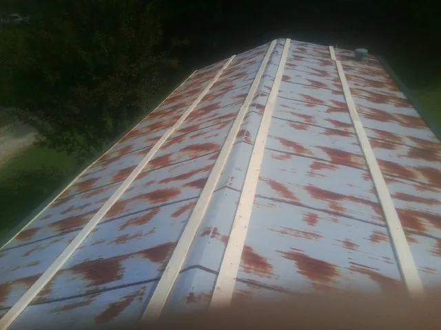 Rusted metal roof panels with new wood purlins before replacement — Storm Damage Roof Repair in Moline by Roofing Brothers
