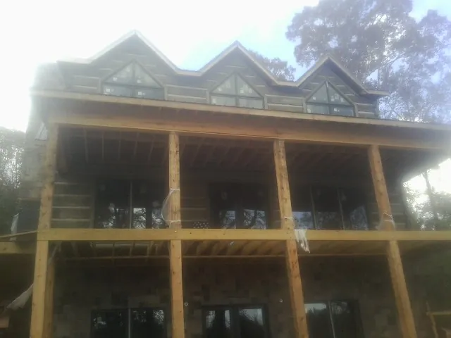 Dormers and porch framing on a large log home under construction — Roof Coating work by our crew in Moline