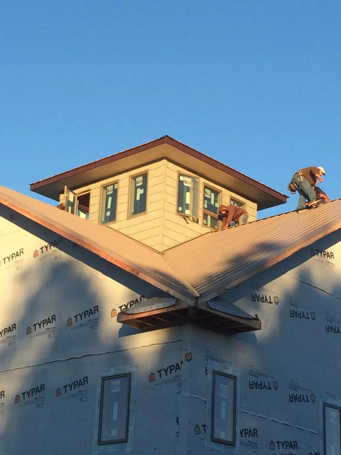 Roofers working around a rooftop cupola on a new metal roof at sunset — Roof Waterproofing in Moline by Roofing Brothers